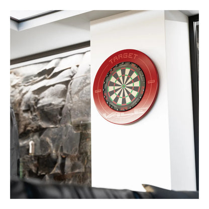 Target TOR Dartboard with red rim on a white wall next to a framed picture of rocks.
