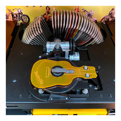 Close-up of a mechanical device with a guitar-shaped component on a yellow background.