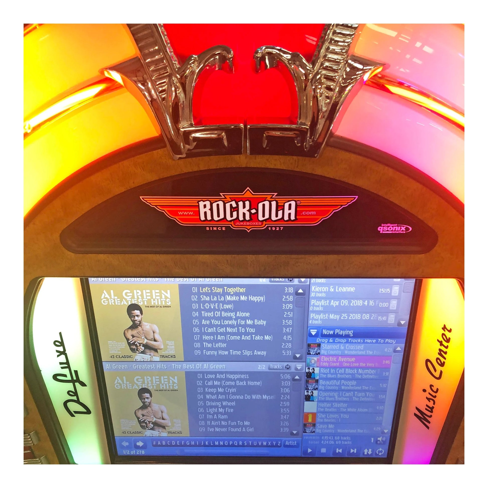 Vintage-style jukebox with 'Rock-Ola' branding and a screen displaying music tracks.