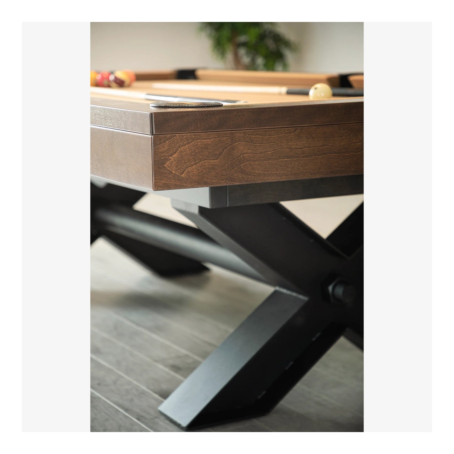 Wooden pool table with metal legs on a wooden floor.